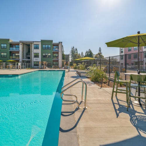 a swimming pool with tables, chairs and umbrellas